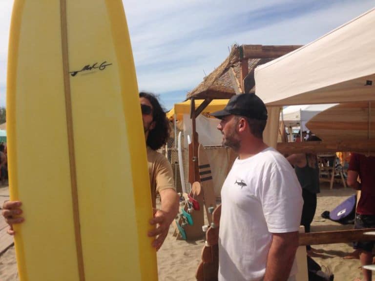 uno shaper itliano mentre mostra la sua creazione ad un surfista
