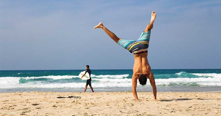 Spiaggia con surfista e verticale per allenare equilibrio